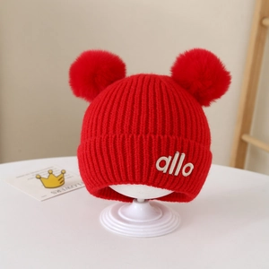 Detailaufnahme der roten Kinder-Strickmütze mit zwei Bommeln und allo Stickerei-Detail