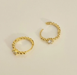 Detailed view of gold beaded hoop earrings with central round white zircon stones