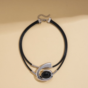 Close-up of a silver spiral pendant with black gemstone on a double-layer cord necklace