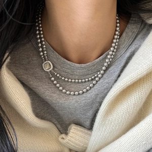 Close-up of a double-layered beaded necklace featuring a square iridescent shell pendant