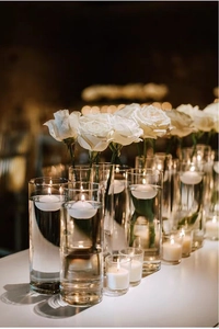 Elegante decoratie met witte drijfkaarsen in glazen vazen en witte rozen voor romantiek