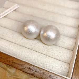 Dettaglio di orecchini di perle vellutate in una scatola per gioielli in velluto beige