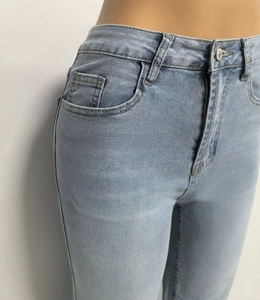 Detail van een lichtblauwe jeans met hoge taille, metalen knoop en stiksel op de voorzak