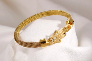Détail du bracelet en maille dorée avec breloque main de Fatma sur fond en tissu