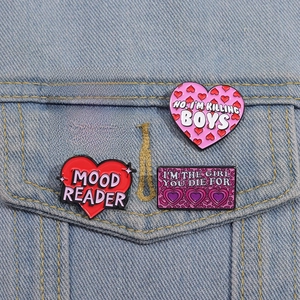 Gros plan de pin's cœurs émaillés roses avec messages inspirants sur veste en jean