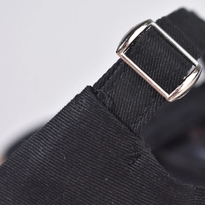 Close-up of black cotton baseball cap with adjustable silver metal buckle and neat stitching
