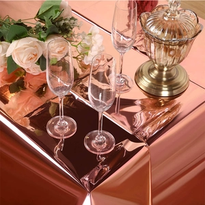 Close-up of shiny rose gold foil tablecloth for party table setting with elegant reflections