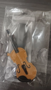 Detailed view of a miniature violin keychain made of brown PU leather with fine stitching