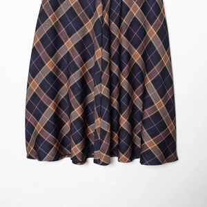 Women's plaid cape skirt in deep blue and brown tartan textile with draped silhouette