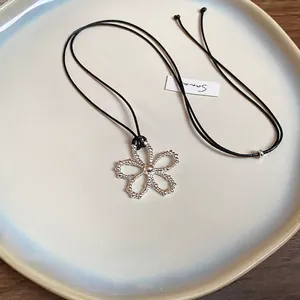 Collier minimaliste en cordon de cire avec pendentif fleur évidée sur plat céramique