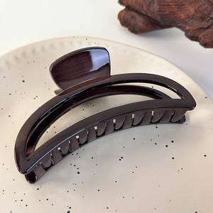 Detail of a large tortoiseshell acrylic crescent hair claw clip on a decorative plate