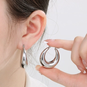 Close-up of polished silver U-shape hoop earrings in a minimalist drop design