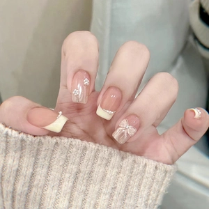 Detailed view of cat-eye press-on nails with 3D pearls, bows, and floral decorations