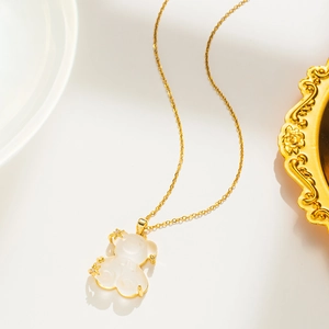 Elegant gold titanium necklace with a translucent bear pendant and gold stars on white surface