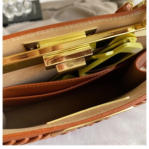 Detailed view of brown woven handbag interior with gold clasp and spacious inner compartment