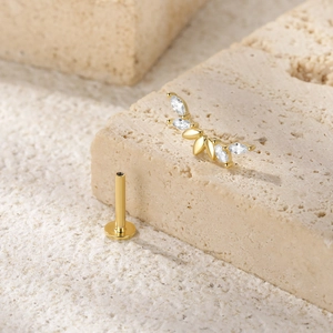 Detail of gold-plated butterfly labret stud with marquise gems on textured stone
