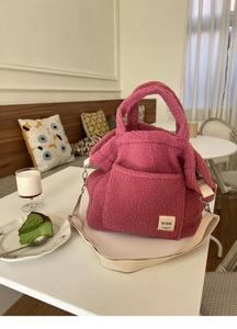 Pink faux shearling tote bag with cream straps shown in a cozy indoor lifestyle setting