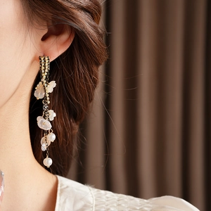 Close-up of floral tassel earrings with pearls and crystals on a model's ear