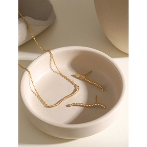 Detail of 18k gold plated wavy necklace and stud earrings set with white zircons