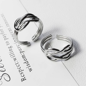 Macro detail of silver titanium steel knot rings featuring minimalist double line braid design