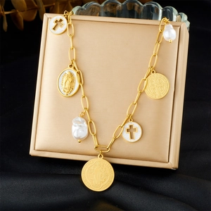 Close-up of golden multi-charm bracelet with religious medals, cross, and pearl detail