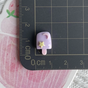 Detailed view of mini purple luminous resin popsicle charm showing size on scale mat