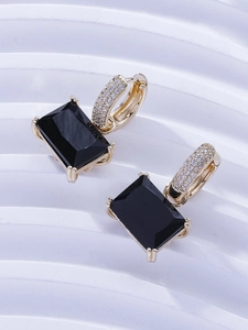 Detail of gold earrings featuring large rectangular black stones and pavé set cubic zirconia