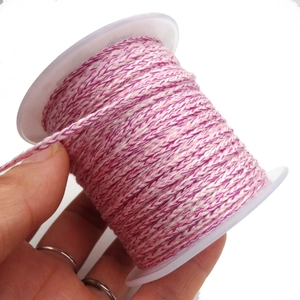 Close-up of pink and white braided DIY cord wrapped on a transparent plastic spool