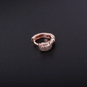 Macro shot of a rose gold earring hoop with sparkling cubic zirconia on a dark background