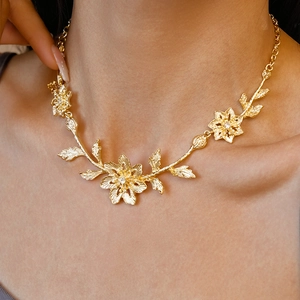 Close-up of golden floral and leaf necklace worn on neck highlighting metallic details