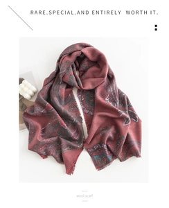Detail of wool scarf with paisley pattern and soft fringe in deep red and teal