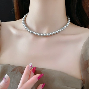 Detail einer grauen Perlenkette am Hals für einen eleganten französischen Vintage-Stil