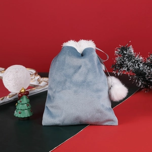 Blue velvet drawstring gift bag with white faux fur trim and pom-poms for Christmas