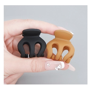 Close-up of small matte pumpkin hair claws in black and yellow for hairstyling
