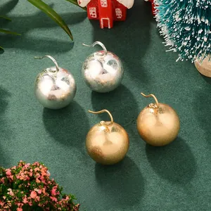 Gros plan de boucles d'oreilles boules dorées mates et argentées sur décor de Noël