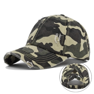 Detail view of distressed camo baseball cap showing unique ponytail hole and frayed brim
