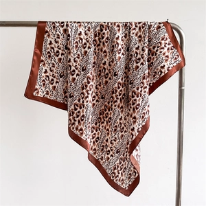 Close-up of leopard print satin scarf featuring classic brown pattern and silk-like texture