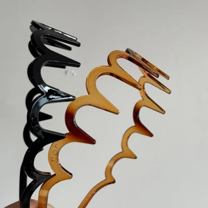 Detail of two wavy non-slip headbands in glossy black and amber tortoiseshell PC material