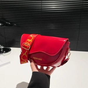 Red patent leather saddle bag with a bold color-block wide strap and metal flip cover