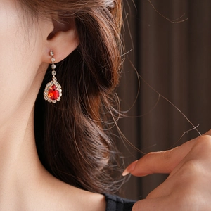 Close-up of red water-drop crystal earrings with tassel diamond chain on model