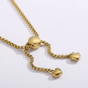 Detail view of gold stainless steel heart charm bracelet with adjustable sliding buckle