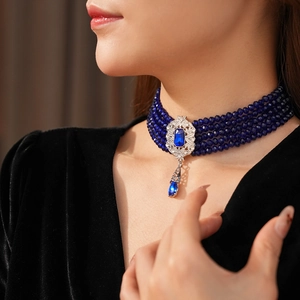 Close-up of vintage blue beaded choker with ornate silver pendant and drop jewel