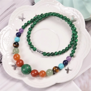 Detailed macro view of 6mm malachite and seven chakra gemstones in a ceramic flower tray