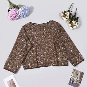 Flat lay of shimmering bronze sequin top with stylish fashion magazines and dried flowers
