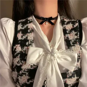 Detail of elegant black velvet choker with a delicate bow and a white pearl pendant