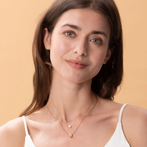 Elegant double layered gold necklace featuring a white pearl and polished heart pendant