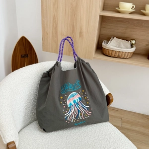 Detail of dark grey nylon tote with jellyfish embroidery and purple braided rope handle
