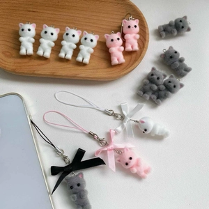 Close-up of cute flocked kitten charms and phone straps with bows on wooden tray