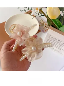 Detail of elegant champagne organza flower hair claw clips with pearls in a French style