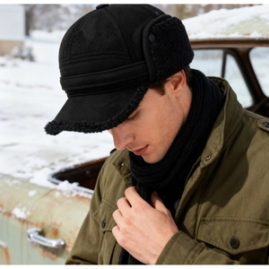 Detail of warm black trapper hat with faux shearling lining and earflaps for cold winter
